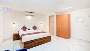 A modern bedroom with a bed, bedside tables, an air conditioner, a wardrobe, and a mirror. - FabHotel Srinidhi Stay Inn - HSR Layout (Bangalore)