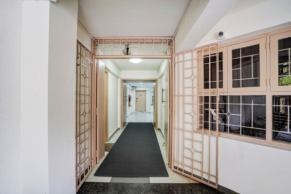 A narrow hallway with a black carpet leading to a door at the end. - FabHotel Srinidhi Stay Inn (Bengaluru)