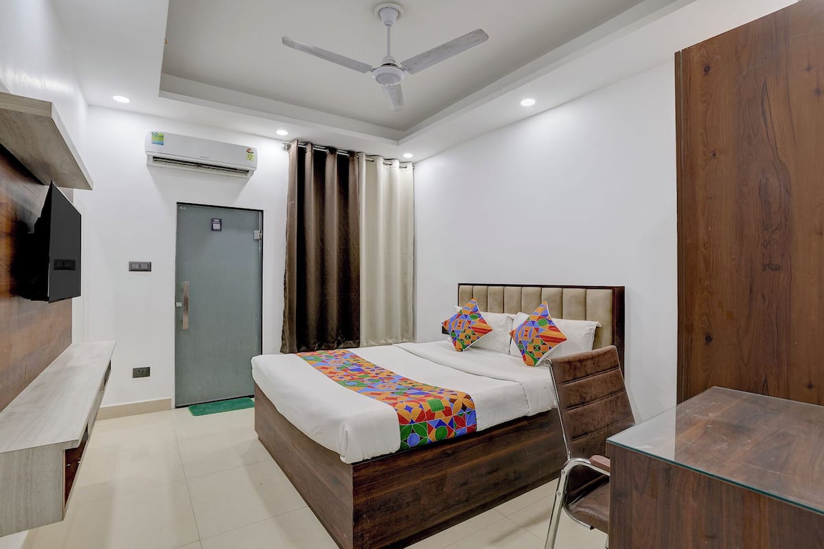 A modern bedroom with a bed, a desk, a wardrobe, and a ceiling fan.