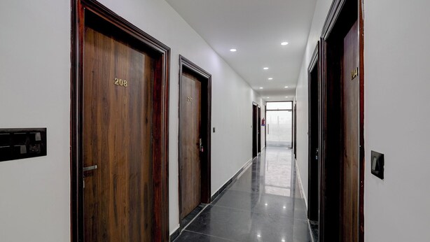 A hallway with wooden doors numbered 208 and 207, leading to a bright room. - Fabhotel Groom Room (Noida)