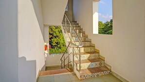 Eine Treppe mit gemusterten Fliesen und Metallgeländern, die zu einem Fenster mit Blick auf Grünanlagen führt.