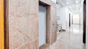 Un interior moderno con una pared de granito, una puerta y una escalera que sube a un nivel superior.