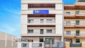 Un moderno edificio de hotel con un letrero azul que dice "fabiHOTELS". Cuenta con varios balcones, una entrada con puerta de reja y un diseño limpio y contemporáneo.