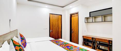 A bedroom with a bed, a desk, and two doors.