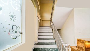 A staircase with white and green marble steps, a metal handrail, and a wooden cabinet on the right.