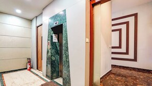A hallway with a marble floor, a fire extinguisher, and a door with a geometric design. - Fabhotel Freedom Star (Mumbai)