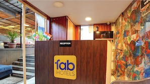 A reception area with a wooden reception desk, a sign for 'Tab Hotels', and a colorful abstract mural on the wall. - Fabhotel Freedom Star (Mumbai)