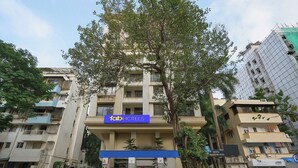 A hotel with a blue sign, a tree in front, and multiple buildings around. - Fabhotel Freedom Star (Mumbai)