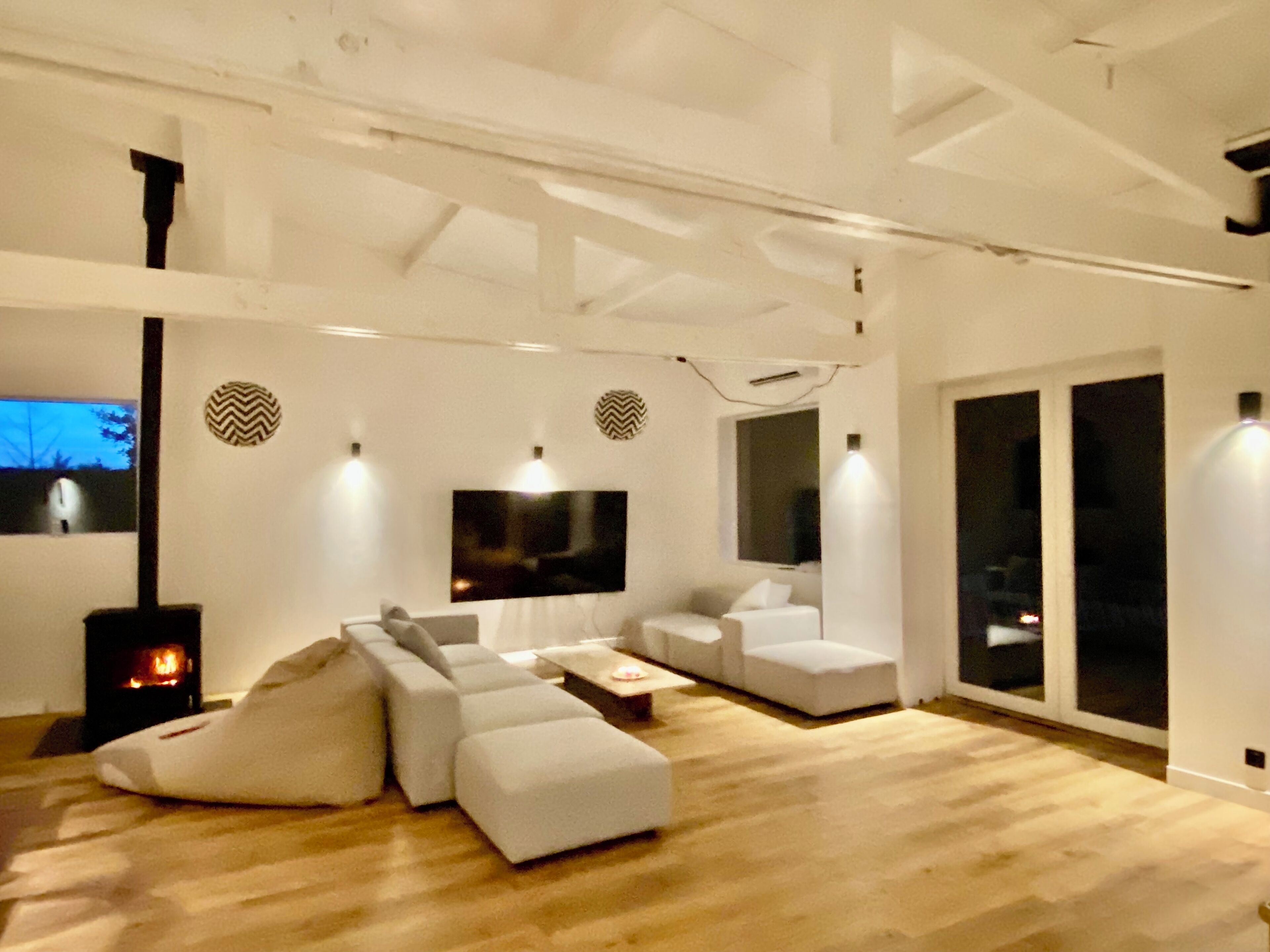 Una sala de estar moderna con un sofá modular, una chimenea y un ventanal grande.