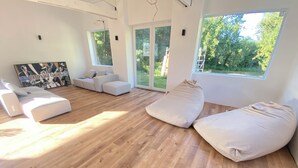 A modern living room with a wooden floor, white sofas, and a large window offering a view of greenery. - L'Atelier, between beach and nature (Barneville-Carteret)