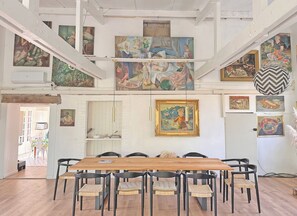 A dining area with a wooden table and black chairs, surrounded by various artworks on the walls. - L'Atelier, between the beach and nature (Barneville-Carteret)