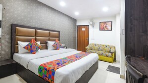 Een hotelkamer met een groot bed, een bank, een televisie en een receptiebalie.