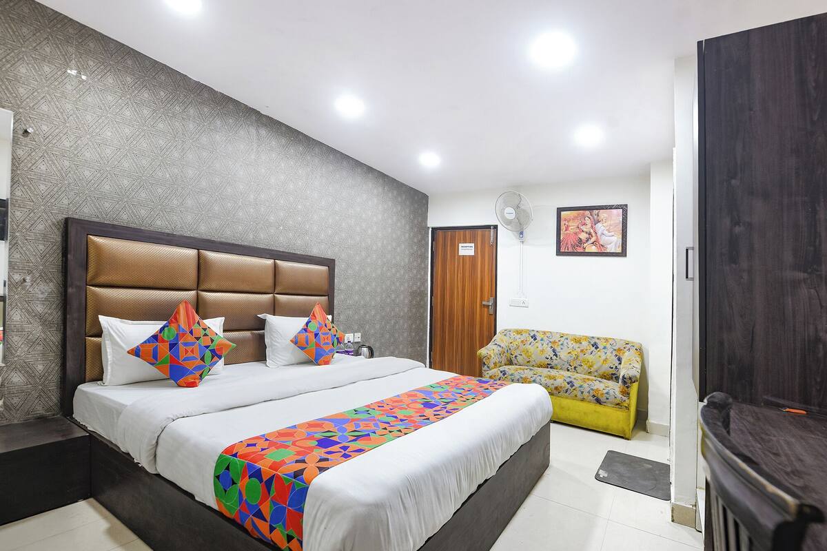 Ein Hotelzimmer mit einem großen Bett, einer Couch, einem Fernseher und einer Rezeption.
