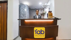 Een receptiebalie met een 'fab hotels' logo, een houten deur, een marmeren wand en een ventilator.