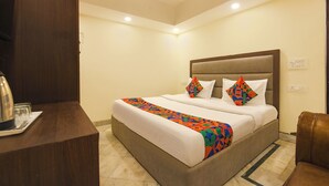 A hotel room with a bed, a desk, and a chair. - Fabhotel South Paradise (New Delhi)