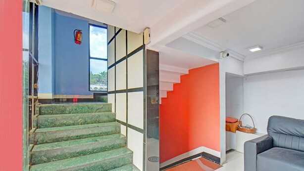 Una escalera con escalones de mármol verde que conduce a una habitación con una pared de acento roja y un sofá gris.