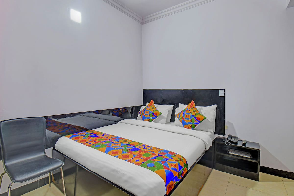 A hotel room with a bed, a chair, a nightstand, and a desk.