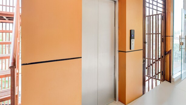 A corridor with orange walls, a white door, and a wooden gate. - FabHotel The Elegant - 150 Meters From Delhi Public School Meerut (Meerut)