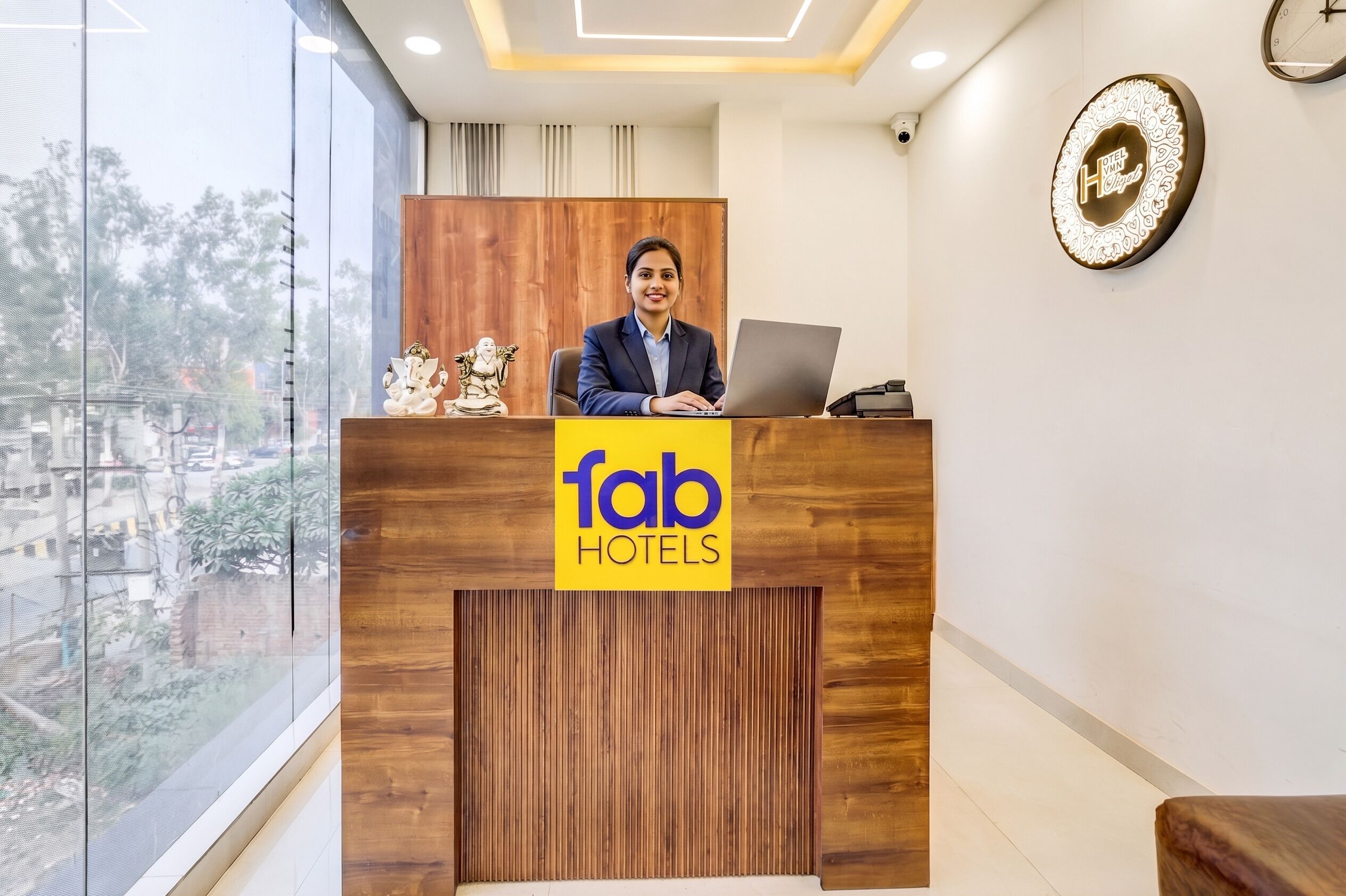 A reception desk with a logo for 'fab hotels,' a wooden panel design, and a clock on the wall.