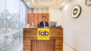 A reception desk with a logo for 'fab hotels,' a wooden panel design, and a clock on the wall. - FabHotel The Elegant - 150 Meters From Delhi Public School Meerut (Meerut)