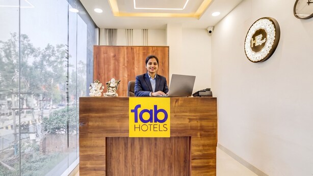 A reception desk with a logo for 'fab hotels,' a wooden panel design, and a clock on the wall. - FabHotel The Elegant - 150 Meters From Delhi Public School Meerut (Meerut)