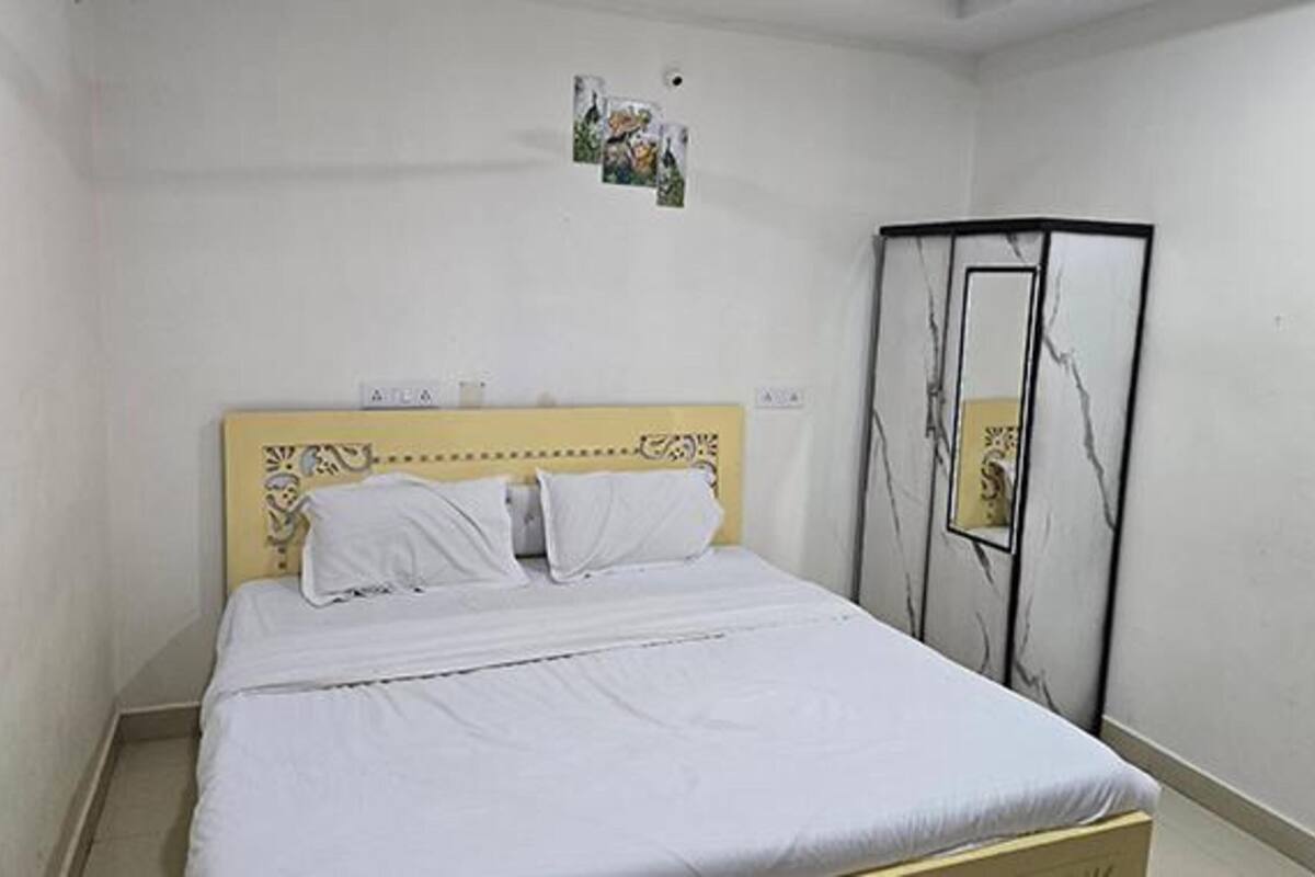 A single bed with a yellow headboard in a room with white walls.