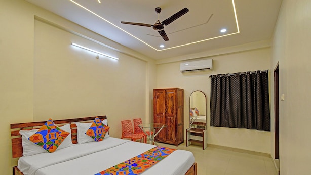 A bedroom with a bed, a ceiling fan, an air conditioning unit, and a window with curtains. - FabHotel Rush Inn (Hyderabad)