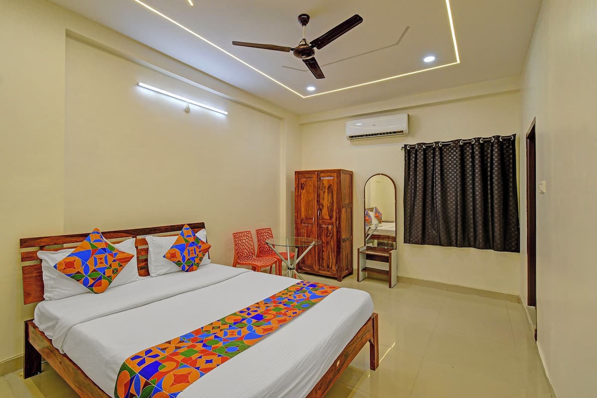 A bedroom with a bed, a ceiling fan, an air conditioning unit, and a window with curtains.