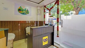 A reception area with a wooden reception desk, a chair, a painting of a landscape, and a sign for 'fab hotels'. - FabHotel Rush Inn (Hyderabad)