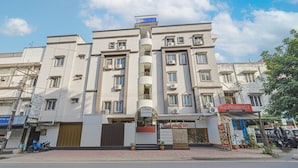 A multi-story hotel with a central entrance, air conditioning units, and a signboard above the entrance. - FabHotel Rush Inn (Hyderabad)