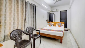 Une chambre à coucher comprenant un lit, deux chaises, un ventilateur de plafond et un appareil de climatisation.