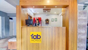 Un comptoir d’accueil avec un revêtement en bois et le logo de la chaîne « fab hotels ».