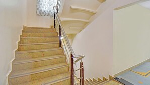Un escalier avec une rampe, un rideau à motifs et un mur de couleur claire.