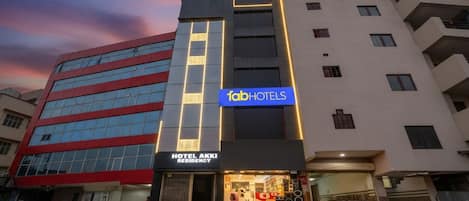 A modern building with a 'fabHOTELS' sign, a 'HOTEL AKKI RESIDENCY' sign, and a storefront with various items on display.