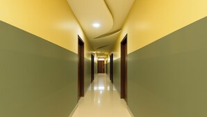 Un pasillo largo y estrecho con puertas a ambos lados, que conduce a una habitación luminosa al final.