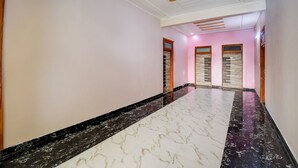 A hallway with marble flooring, pink walls, and wooden door frames. - Fabhotel Sunshine Inn (Lucknow)