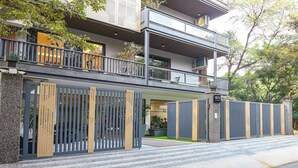 Ein modernes, zweistöckiges Haus mit Balkon, geschlossenem Eingangstor und einer Steinsäule mit einem Schild.
