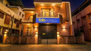 Un edificio con un letrero que dice “fabHOTELS  ” en la entrada, con un diseño moderno y un acceso principal destacado, además de un camino de entrada con portones.