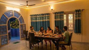 Comedor con una mesa dispuesta para seis personas, rodeado de cortinas azules y un arco decorativo.