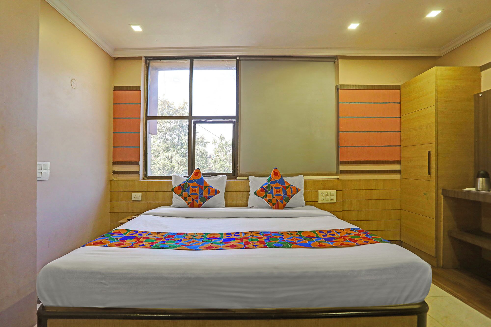Quarto de hotel com cama, janela e guarda-roupa de madeira.