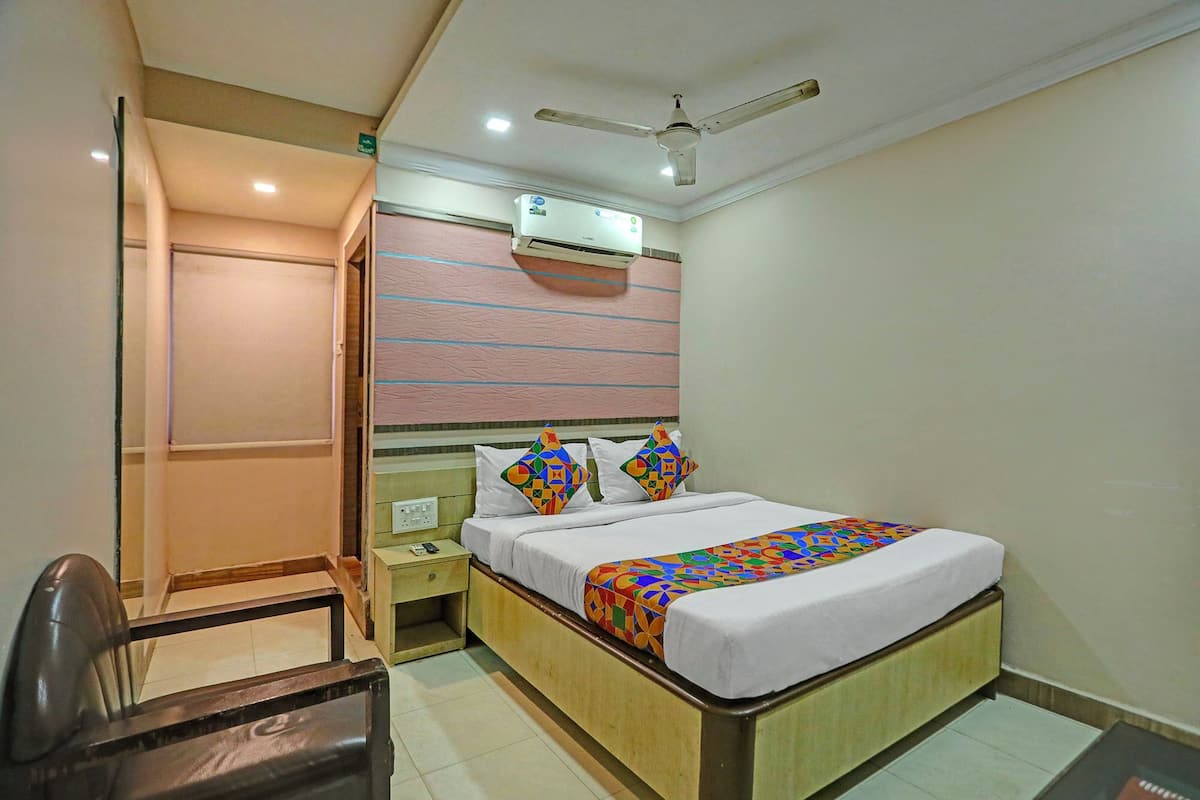 Une chambre d’hôtel avec un lit, une table de chevet, une chaise et un ventilateur de plafond.