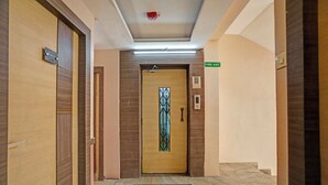 Ein Hotelgang mit Holztüren, einem Feuerschutzausgang und einer modernen Leuchte.