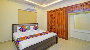 Une chambre à coucher comprenant un lit, un ventilateur de plafond, un climatiseur et des armoires en bois.