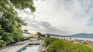 A swimming pool with lounge chairs, a yellow umbrella, and a view of a lake and mountains.