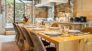 A dining area with a long wooden table set for a meal, stone walls, and a stone fireplace.