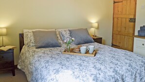 A bedroom with a bed, two bedside lamps, a wooden door, and a tray with a cup and a pastry. - 2 bedroom accommodation in Fordwich, Canterbury (Fordwich, Canterbury)