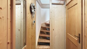 Un interior de madera con una escalera, puertas de madera y una lámpara fijada a la pared.