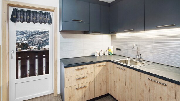Una cocina con armarios de madera, encimera negra y pileta de acero inoxidable.