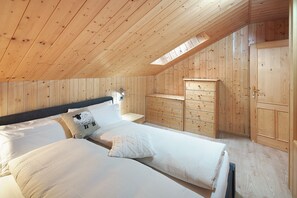 Una habitación con paneles de madera, una cama, un aparador y un tragaluz.