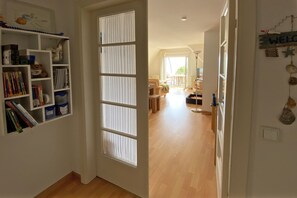 A hallway leading to a living area with a bookshelf, a sliding door, and a welcome sign. - Apartment at the Sandwall with 3 rooms on approx. 55m² with sea view (Wyk auf Föhr)